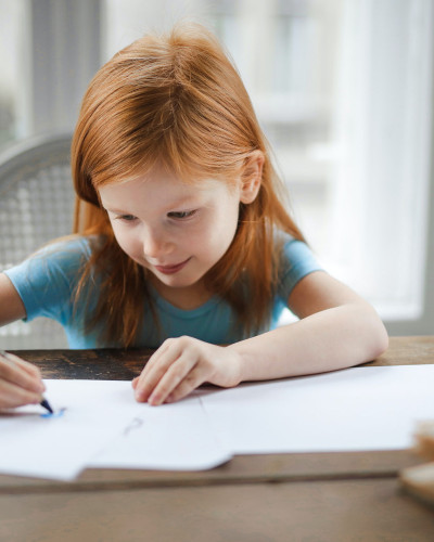 Jeune fille qui dessine avec des crayons à colorier.